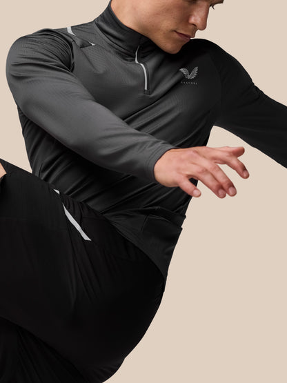 Close-up of a man wearing the charcoal Apex Training Winterised ¼ Zip top, highlighting the zip neck and reflective detailing.