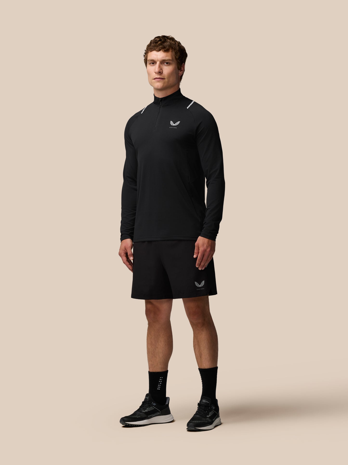 Man wearing black Apex Training quarter zip top with reflective shoulder accents and Castore logo on chest