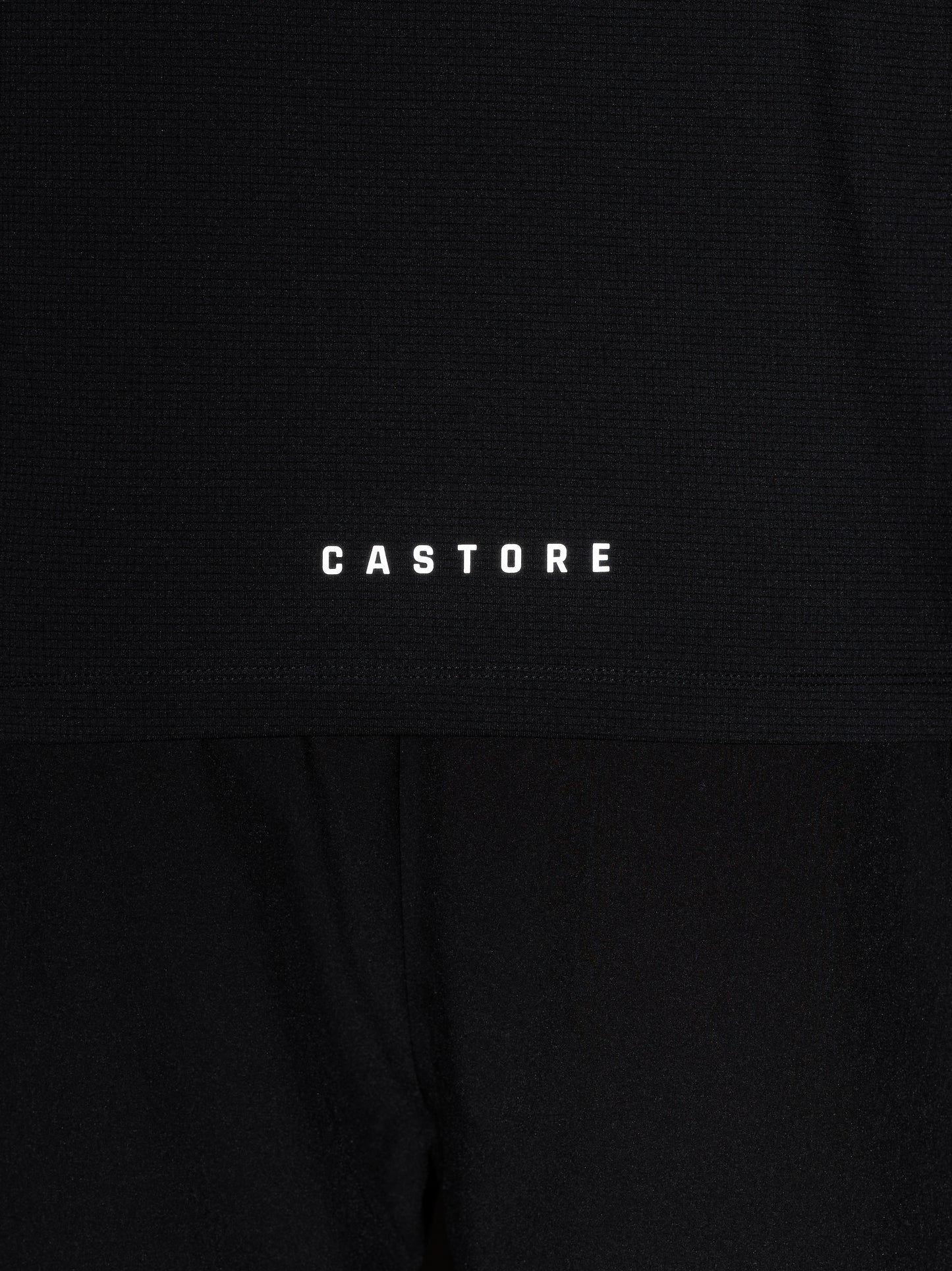 Close up of black knit Apex top with Castore wing logo and CASTORE wordmark on the chest