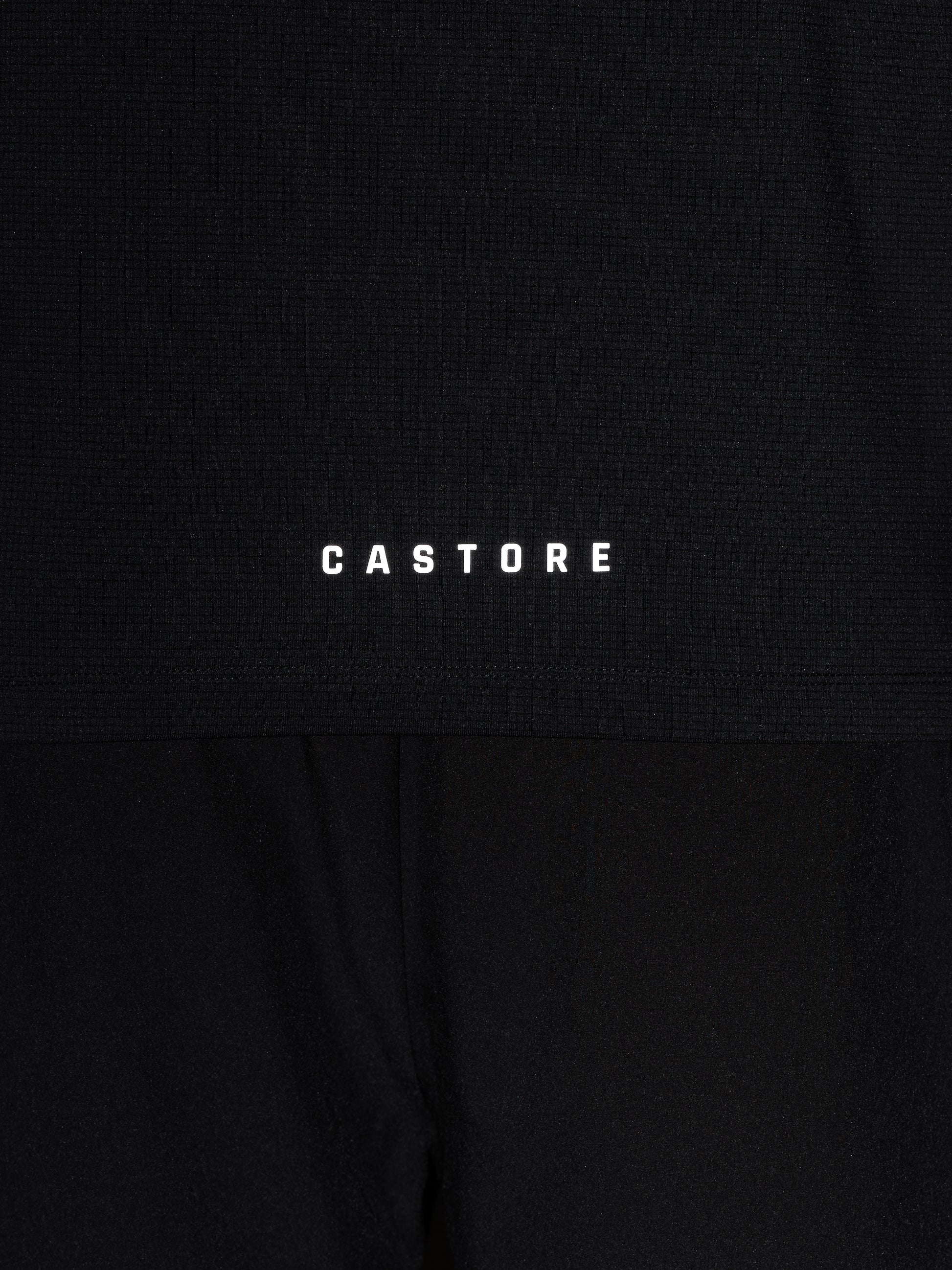 Close up of black knit Apex top with Castore wing logo and CASTORE wordmark on the chest