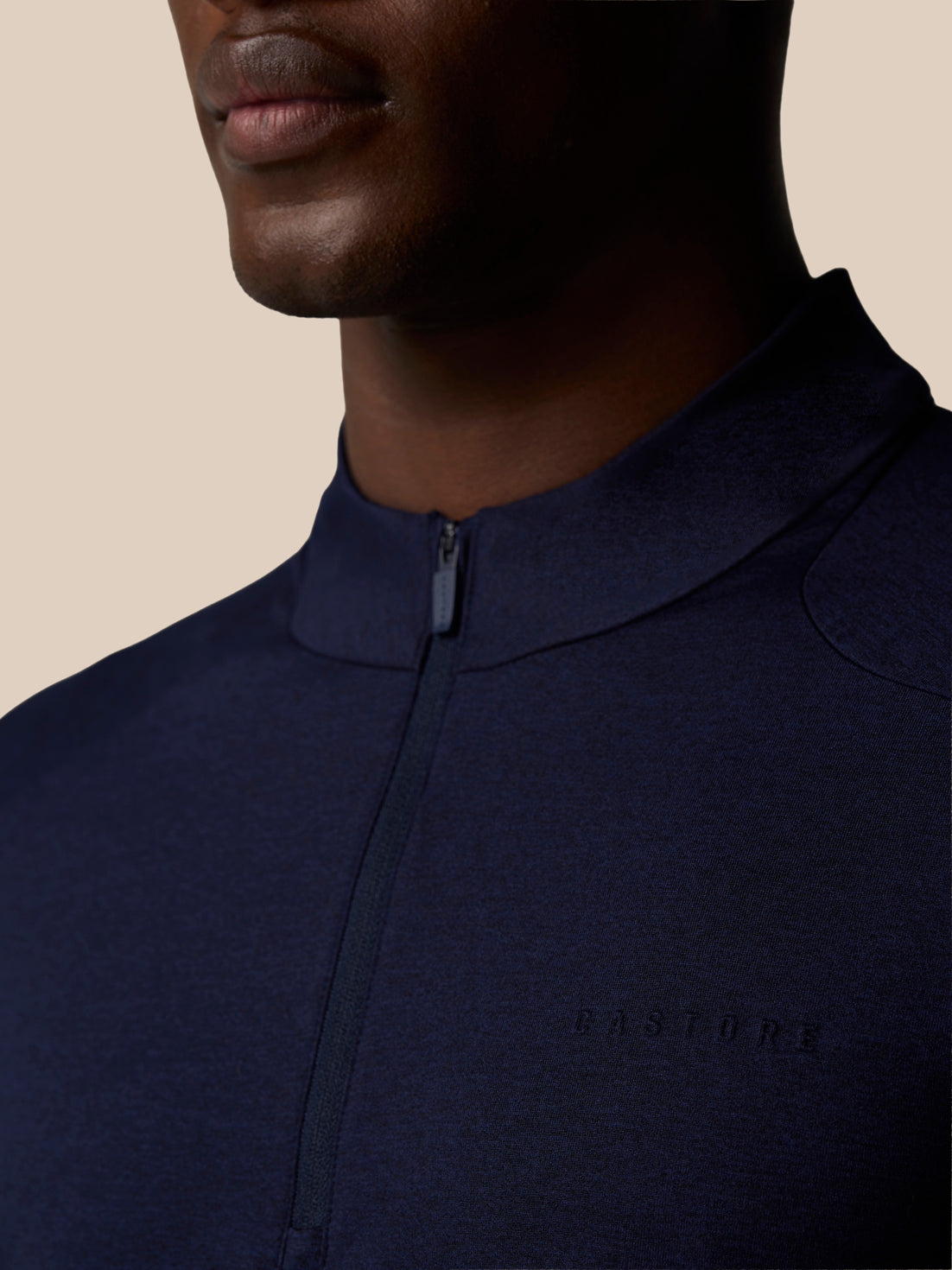Close-up of navy Elevated Lifestyle quarter-zip top showing center front zip and left chest Castore logo