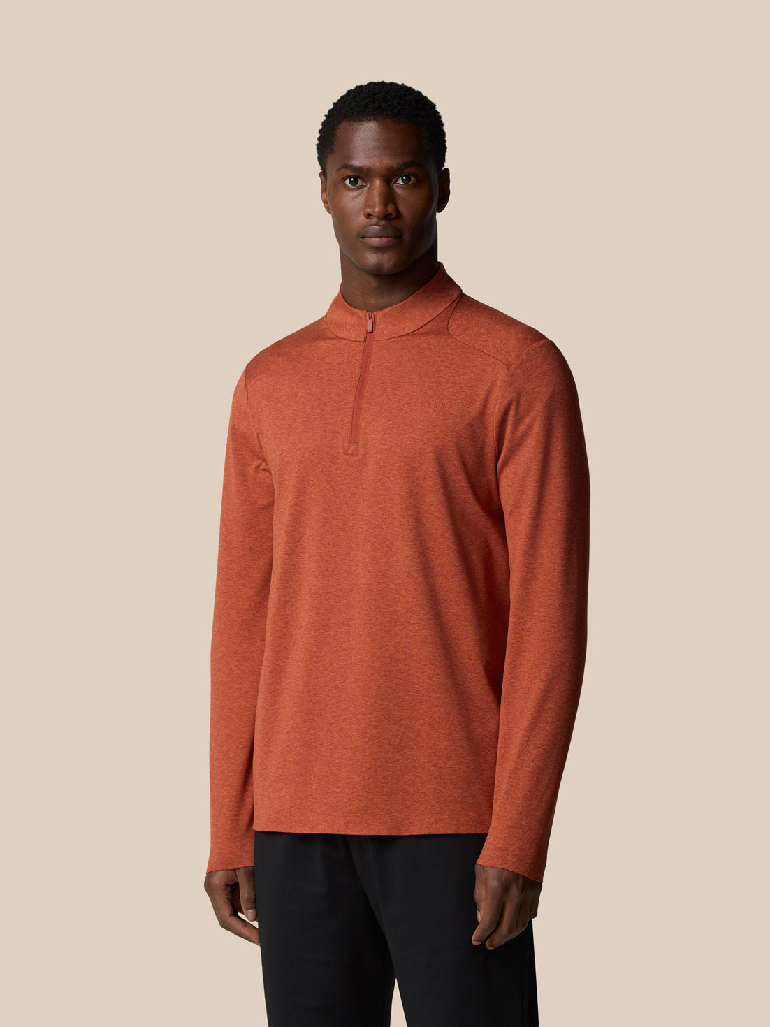 Male model wearing dark rust elevated lifestyle quarter zip top with front zipper and Castore branding on the chest