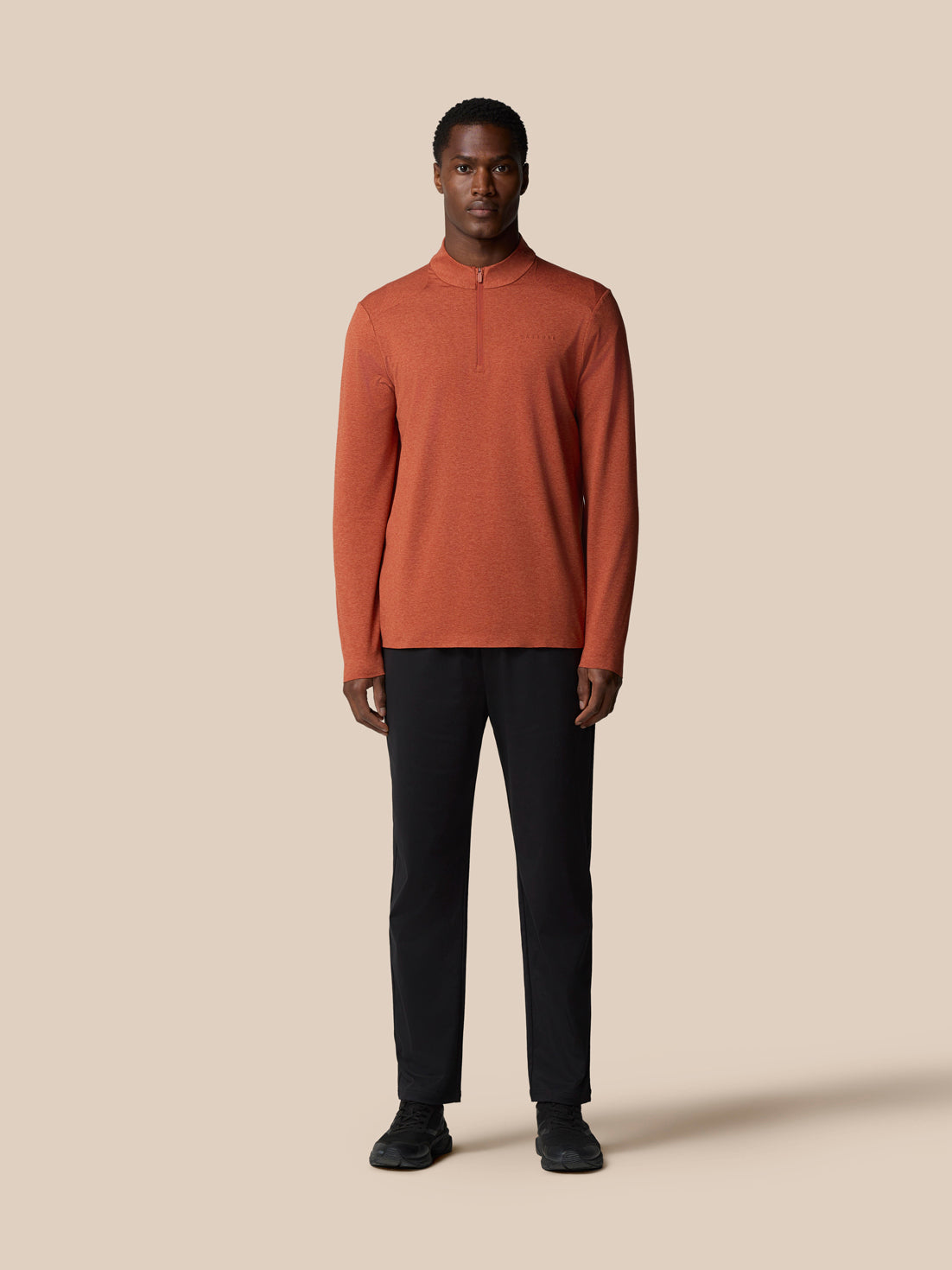 Rear three quarter view of dark rust elevated lifestyle quarter zip top on a male model