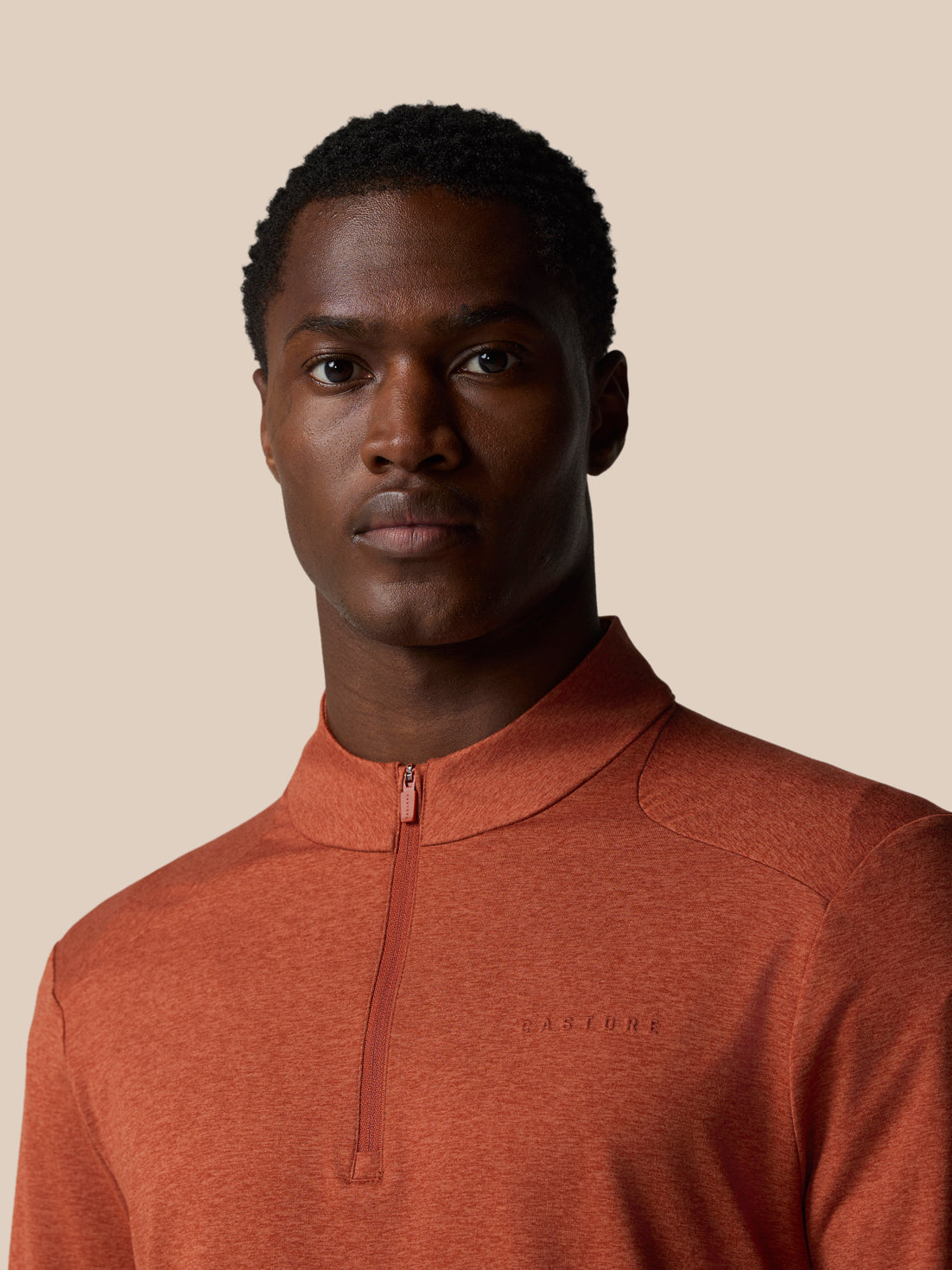 Front view of a model wearing the dark rust Elevated Lifestyle quarter zip top with the neck zipper partially visible