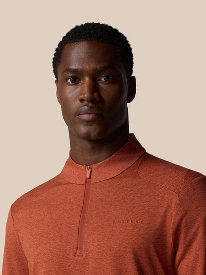Front view of a model wearing the dark rust Elevated Lifestyle quarter zip top with the neck zipper partially visible