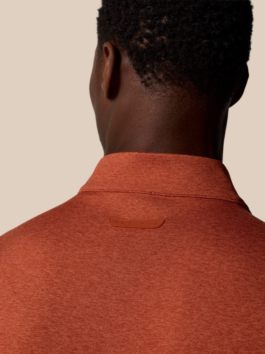 Back view of the rust colored 1/4 Zip Top showing collar seam and a small Castore badge on the upper back