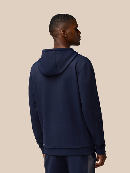 Back view of a model wearing a navy Flex Lifestyle Thermo Hoodie with hood down against a beige background