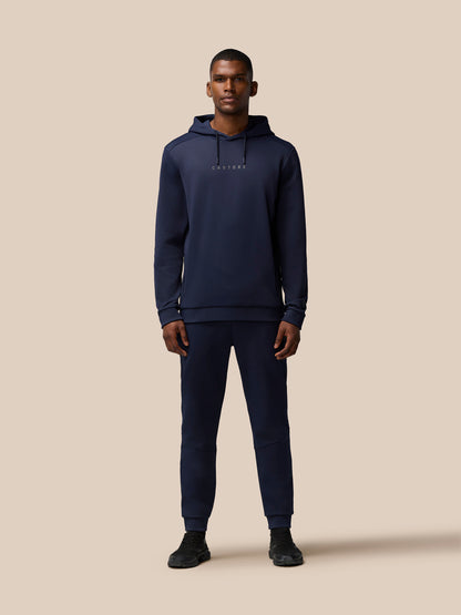 Full body shot of a man in navy Flex Lifestyle Thermo Hoodie with hood up and Castore logo on chest