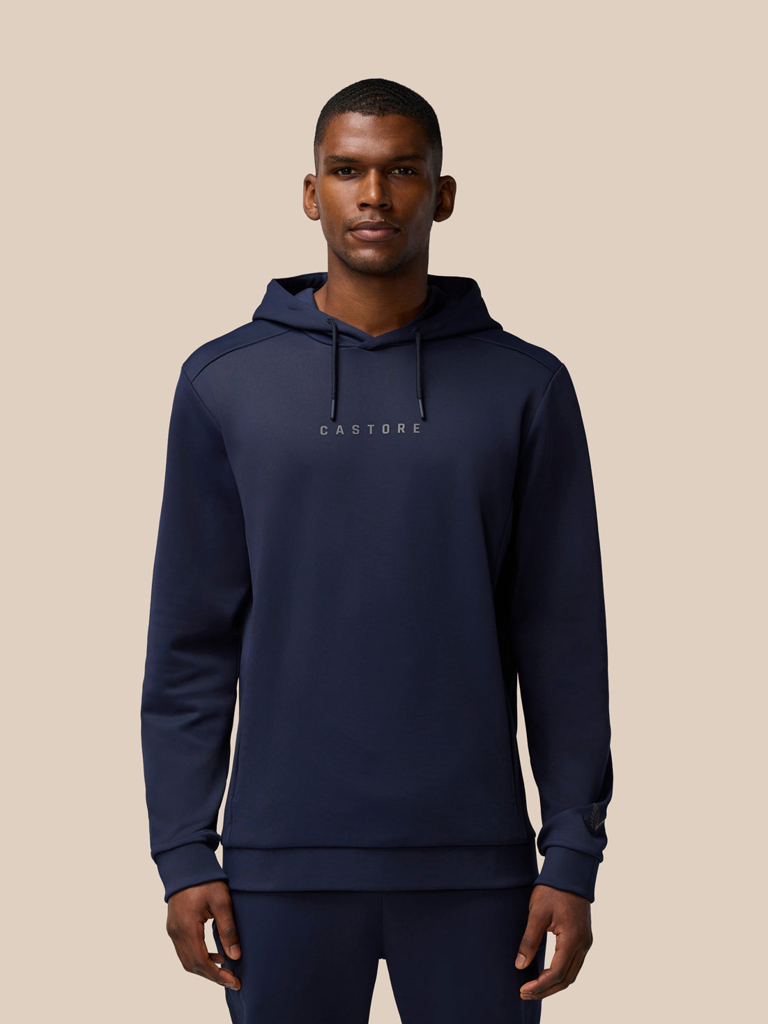 Male model wearing navy Flex Lifestyle Thermo Hoodie featuring Castore wordmark at center chest and logo on left cuff