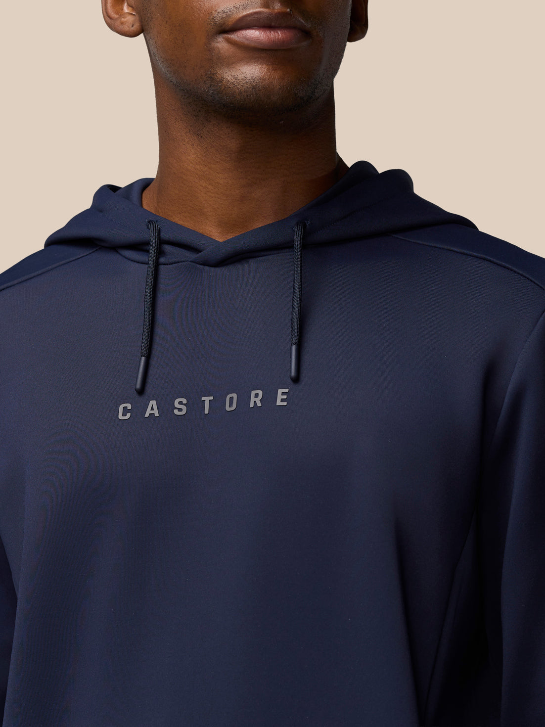 Close-up of navy hoodie chest showing Castore logo and hood drawstrings