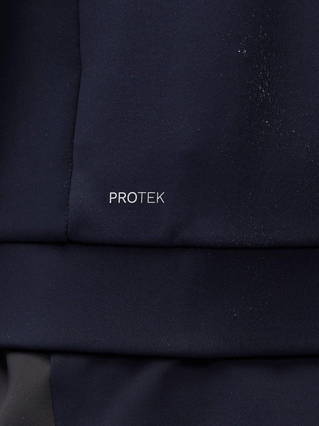 Close-up of navy sleeve with water droplets and ProTek logo on the sleeve.