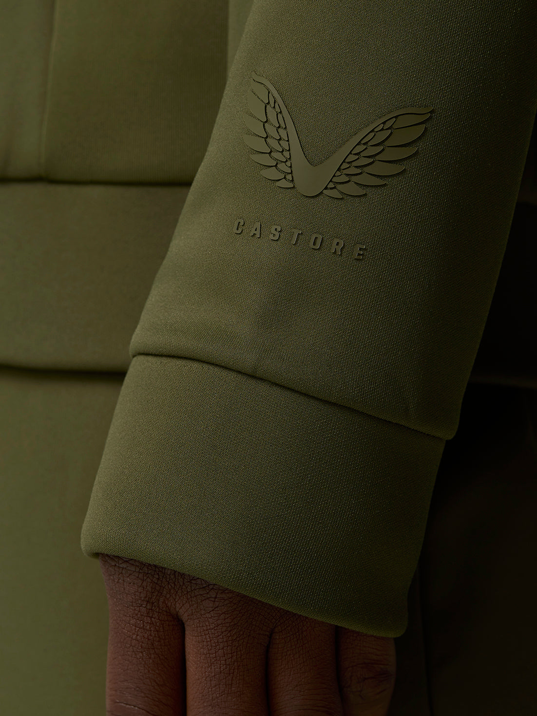 Castore wing logo and wordmark embossed on an olive green sleeve