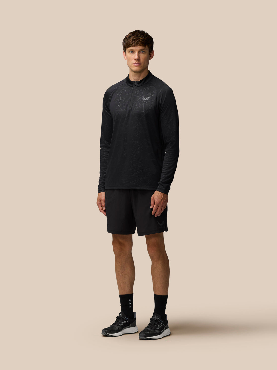Rear view of model wearing black Adapt Training top with all-over geometric print.