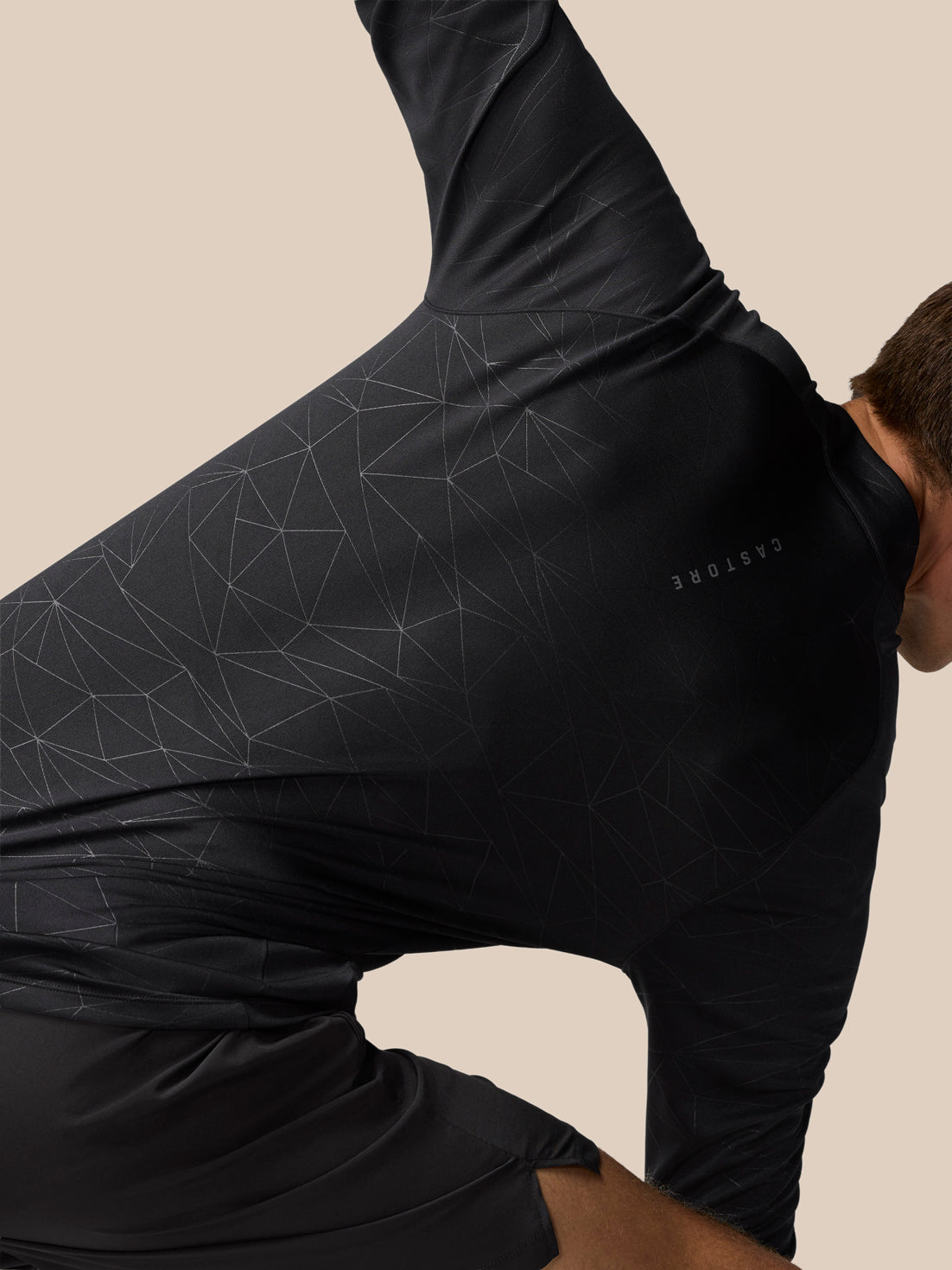 Close up of front of black Adapt Training Top showing geometric pattern and Castore logo at left chest