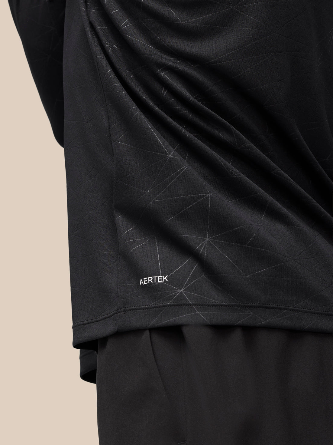 Back view highlighting geometric print and AerTek label near hem on the black Adapt Training Top