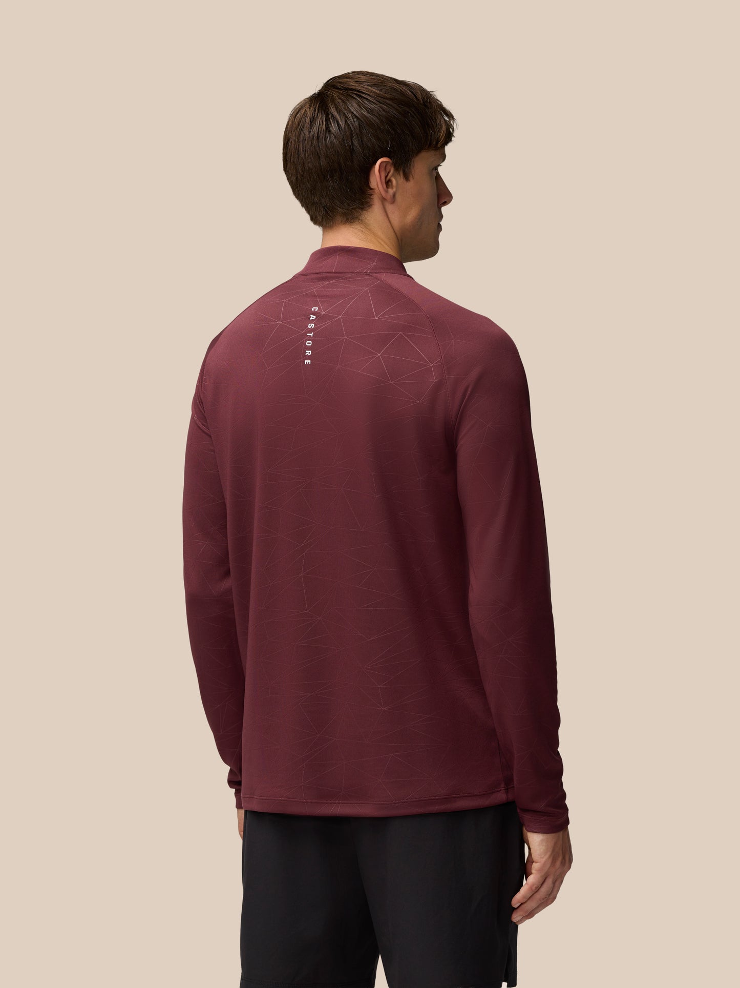 Back view of a man wearing plum Adapt Training 1/4 Zip Top with geometric print and Castore wordmark at the back neck