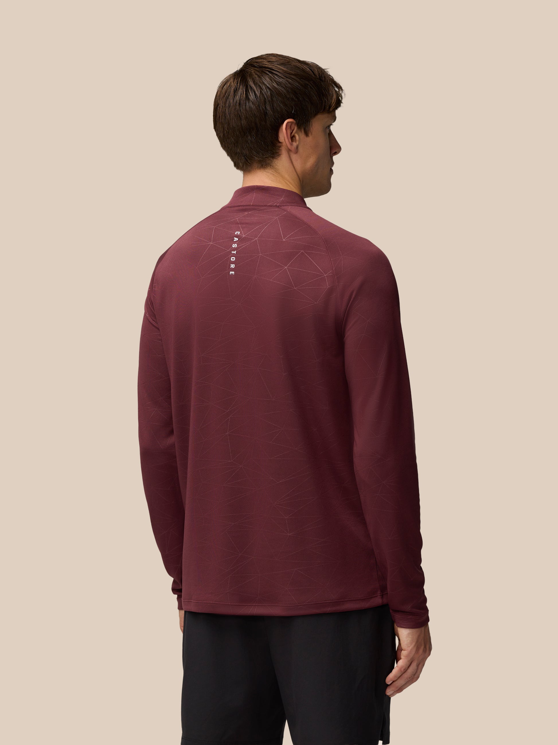 Back view of a man wearing plum Adapt Training 1/4 Zip Top with geometric print and Castore wordmark at the back neck
