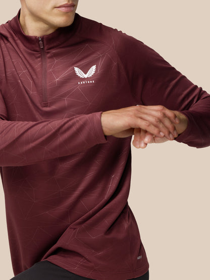 Model wearing plum Adapt Training 1/4 Zip Top with geometric line print and Castore logo on chest with center front zip