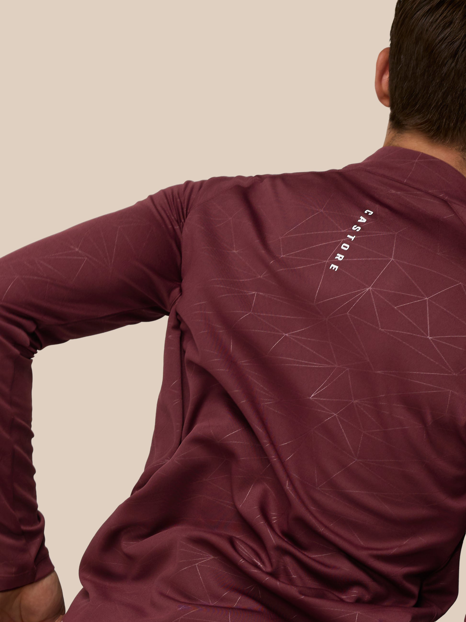 Back right angle of a man wearing plum Adapt Training 1/4 Zip Top showing the geometric print and Castore wordmark along the back neck
