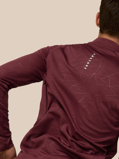 Back right angle of a man wearing plum Adapt Training 1/4 Zip Top showing the geometric print and Castore wordmark along the back neck