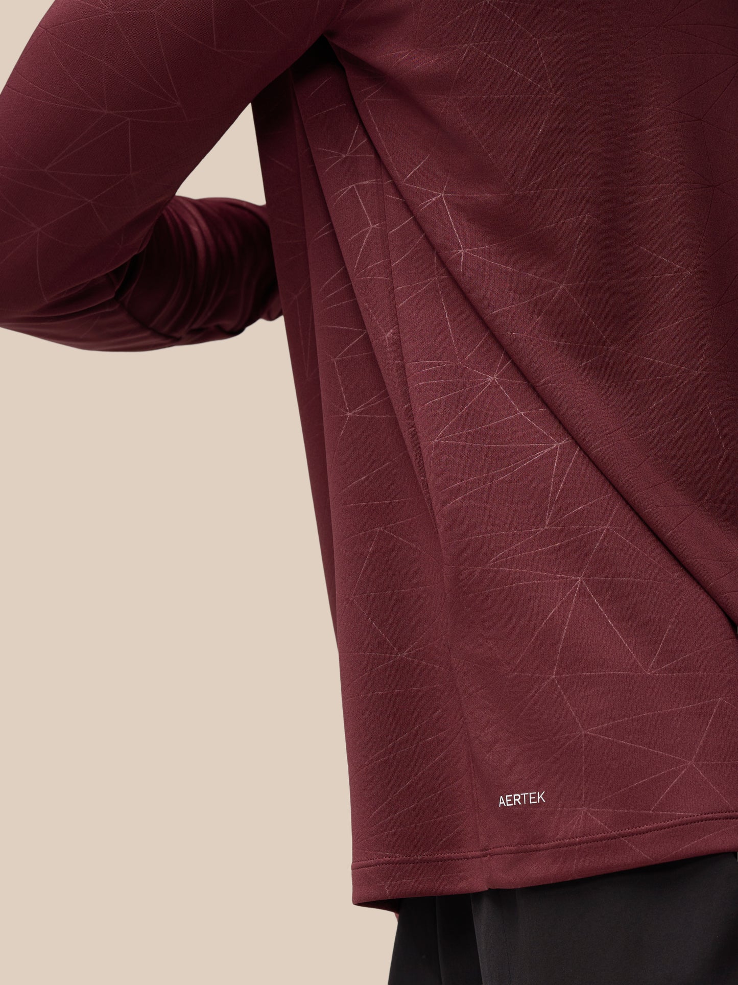 Close-up of plum Adapt Training fabric with geometric lines and AERTEK branding.