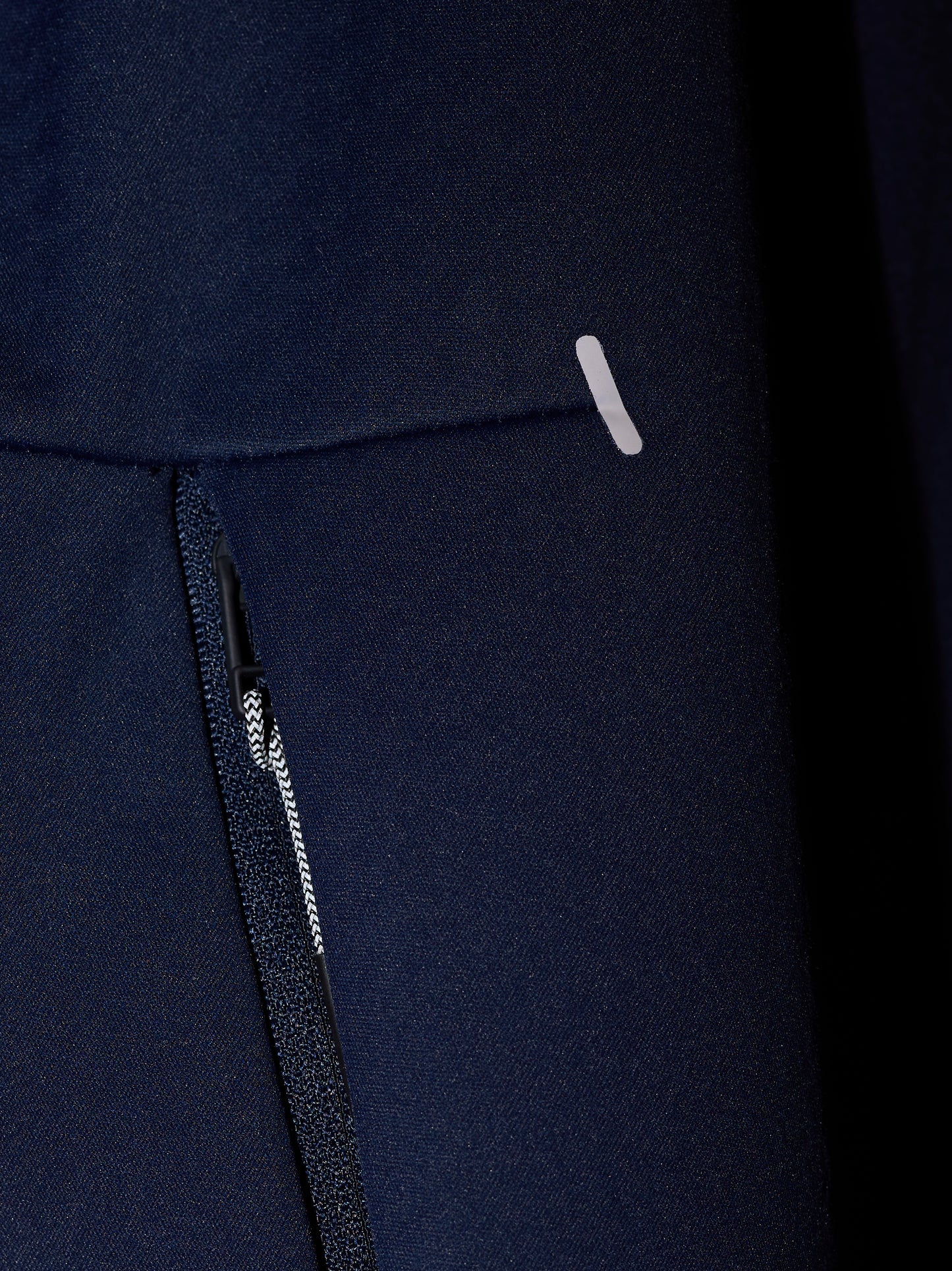 Close-up of navy Garcia 3.0 Hoodie fabric showing a zipper and small reflective tab.