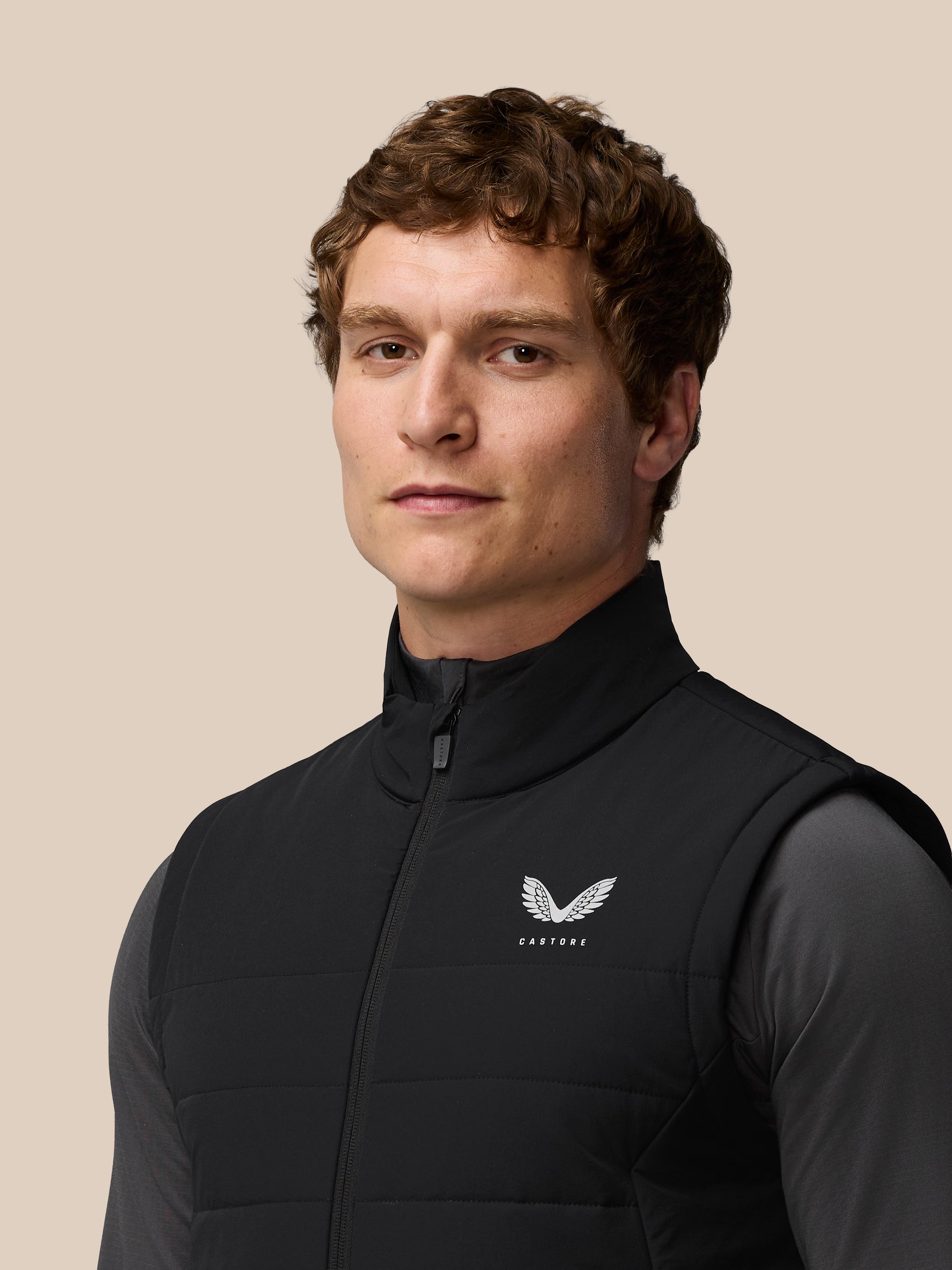 Three quarter back view of a man wearing a black Apex Training Gilet with Castore logo on the chest