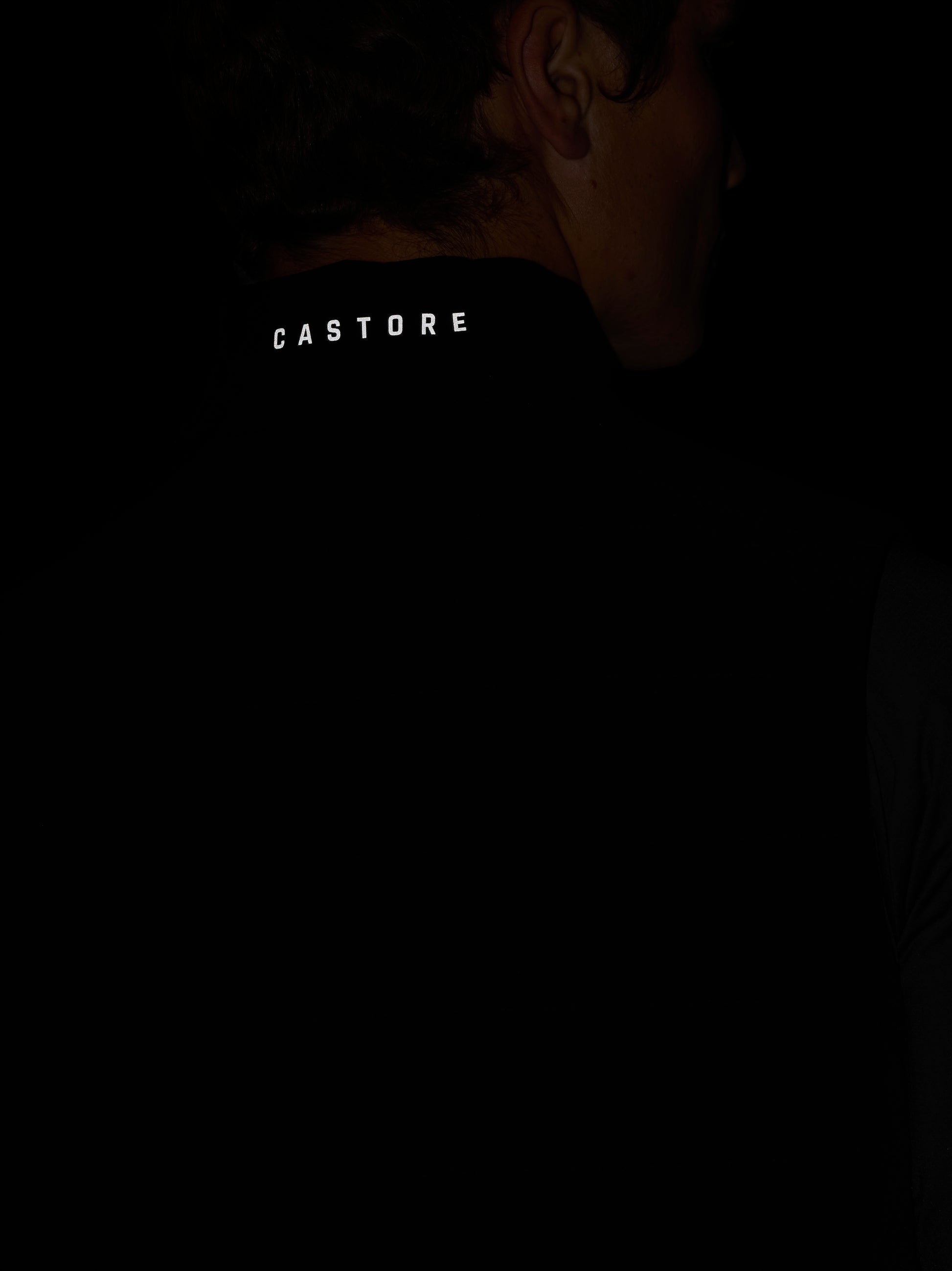 Back of neck close up on black Apex Gilet showing Castore branding on the zipper pull