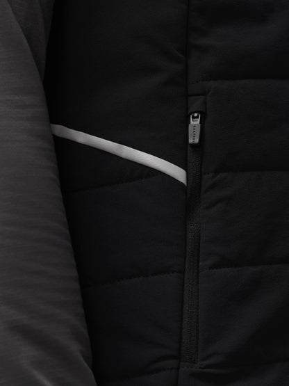 Close up detail of black padded Apex Gilet zipper with Castore branding and a light reflective stripe