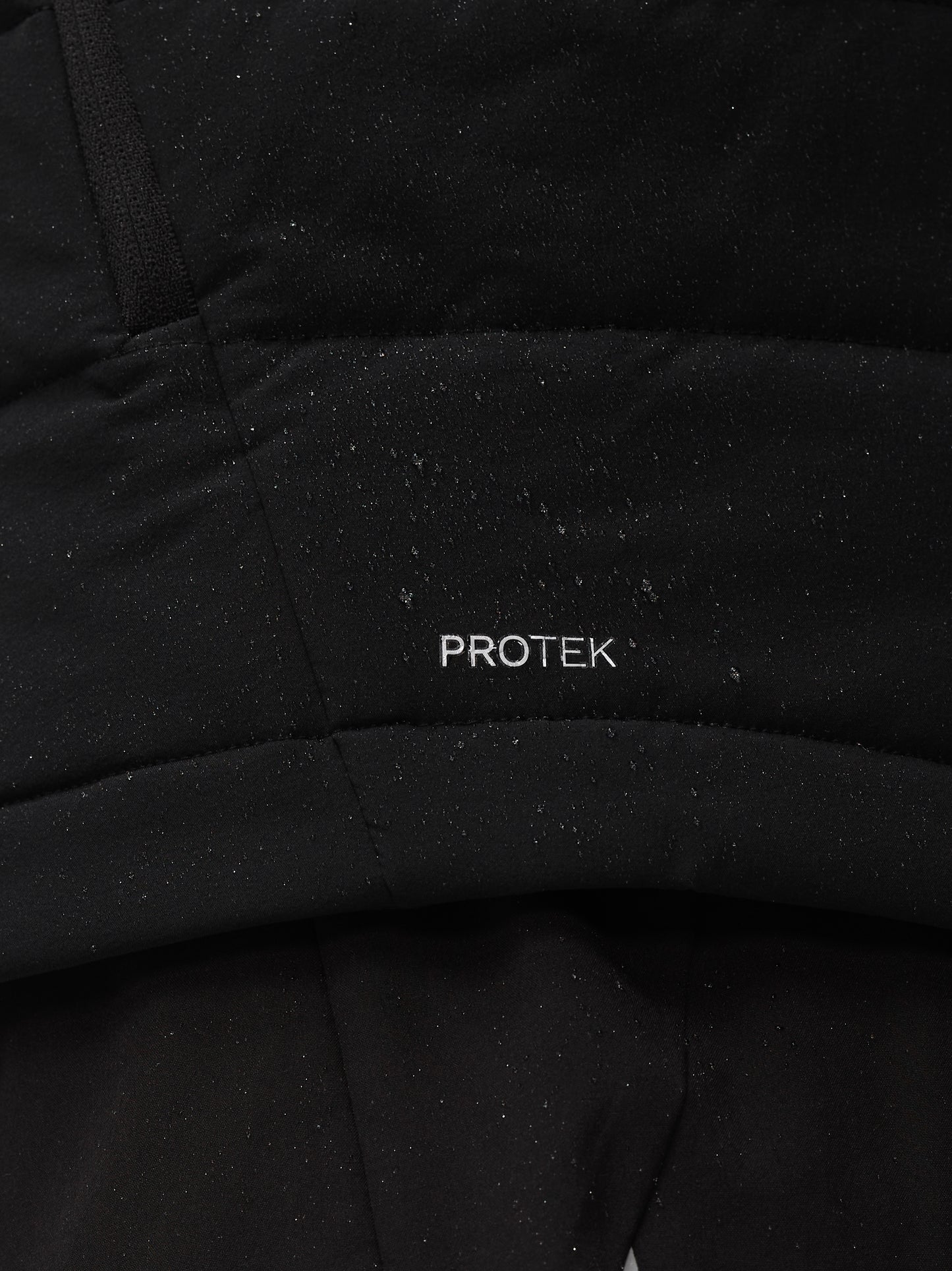 Close up of black Apex Training Gilet fabric with ProTek label and seam details