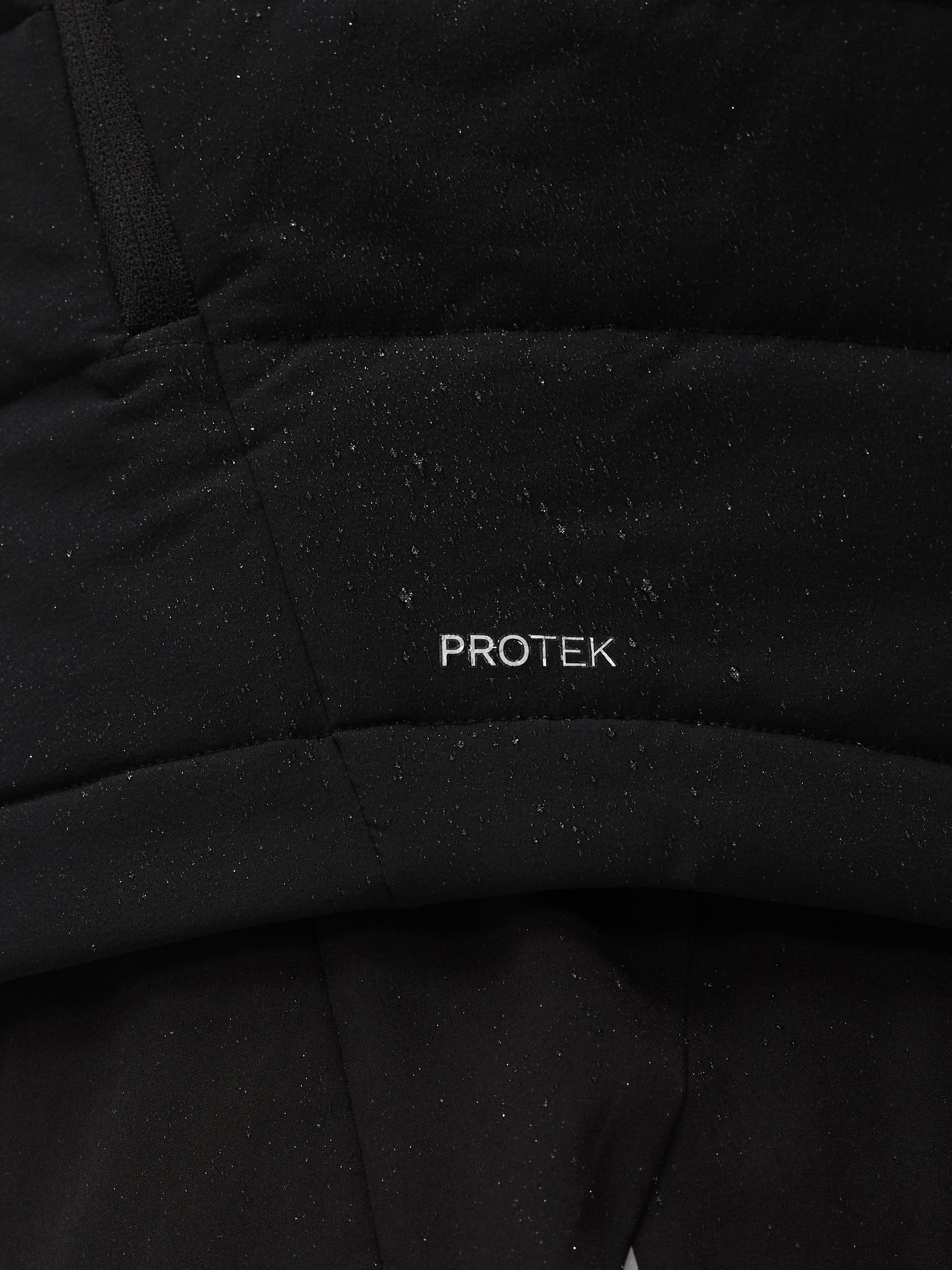 Close up of black Apex Training Gilet fabric with ProTek label and seam details