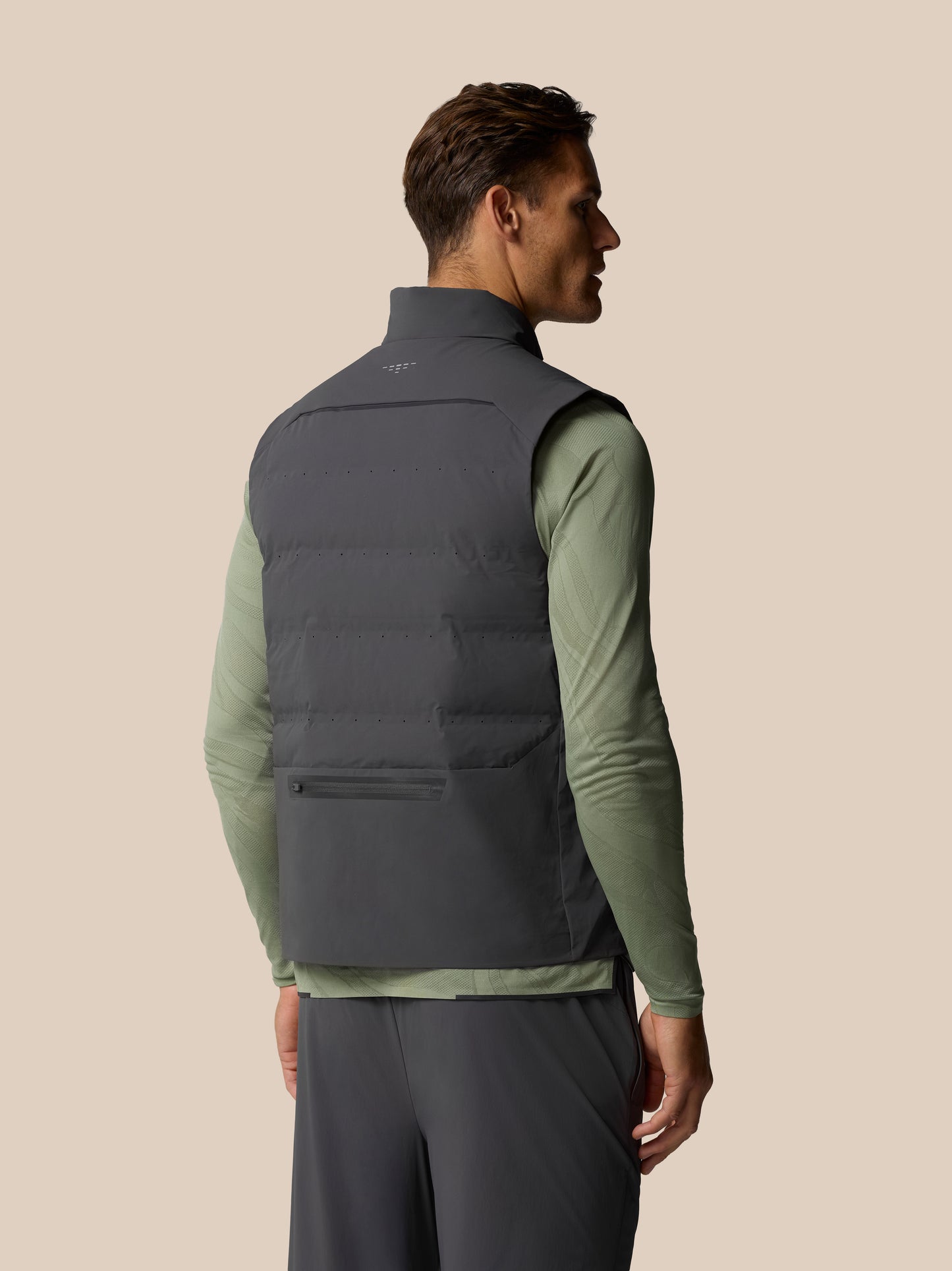 Back view of a man wearing Zone Training LVS Insulated Gilet in gunmetal gray sleeveless vest over a green top