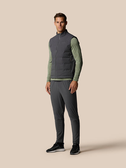 Male model wearing Zone Training LVS Insulated Gilet in gunmetal over olive green long sleeve top, full body shot