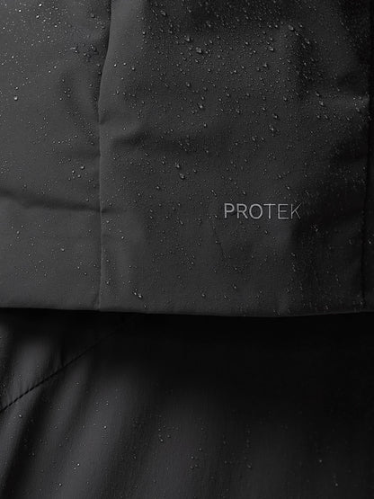 Close-up of dark jacket fabric with PROTEK branding and water droplets on the surface