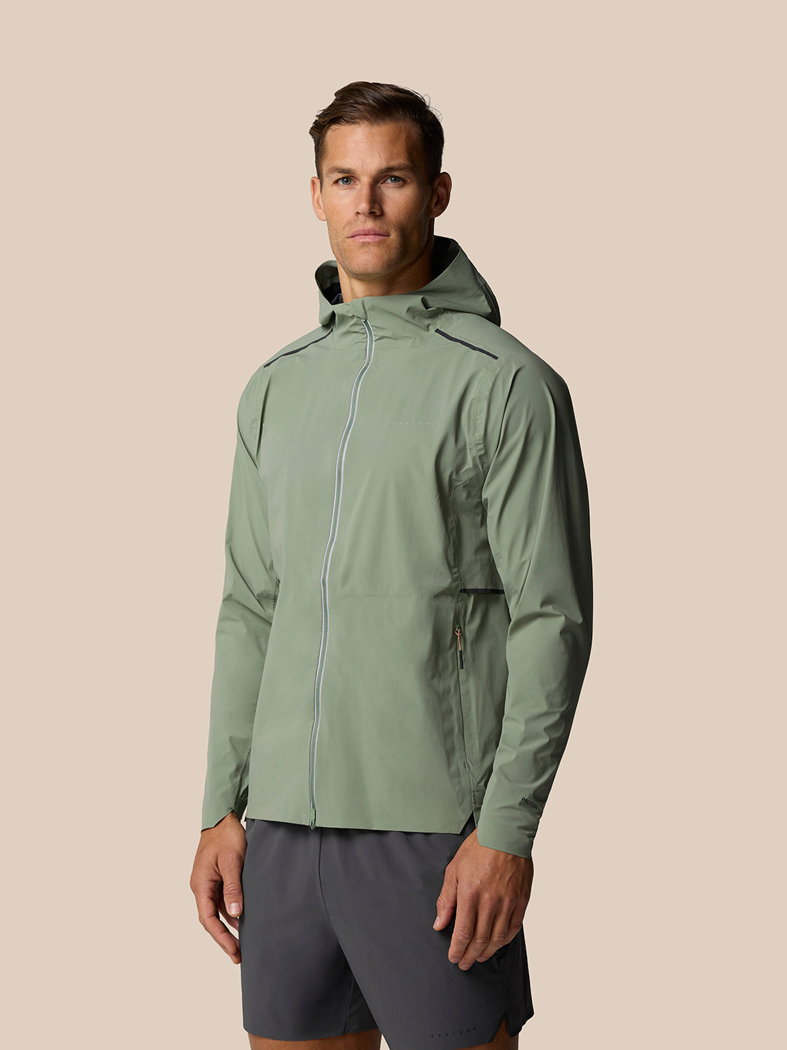 Male model wearing Zone Training LVS Jacket in Thyme with reflective details front view showing full zip and hood