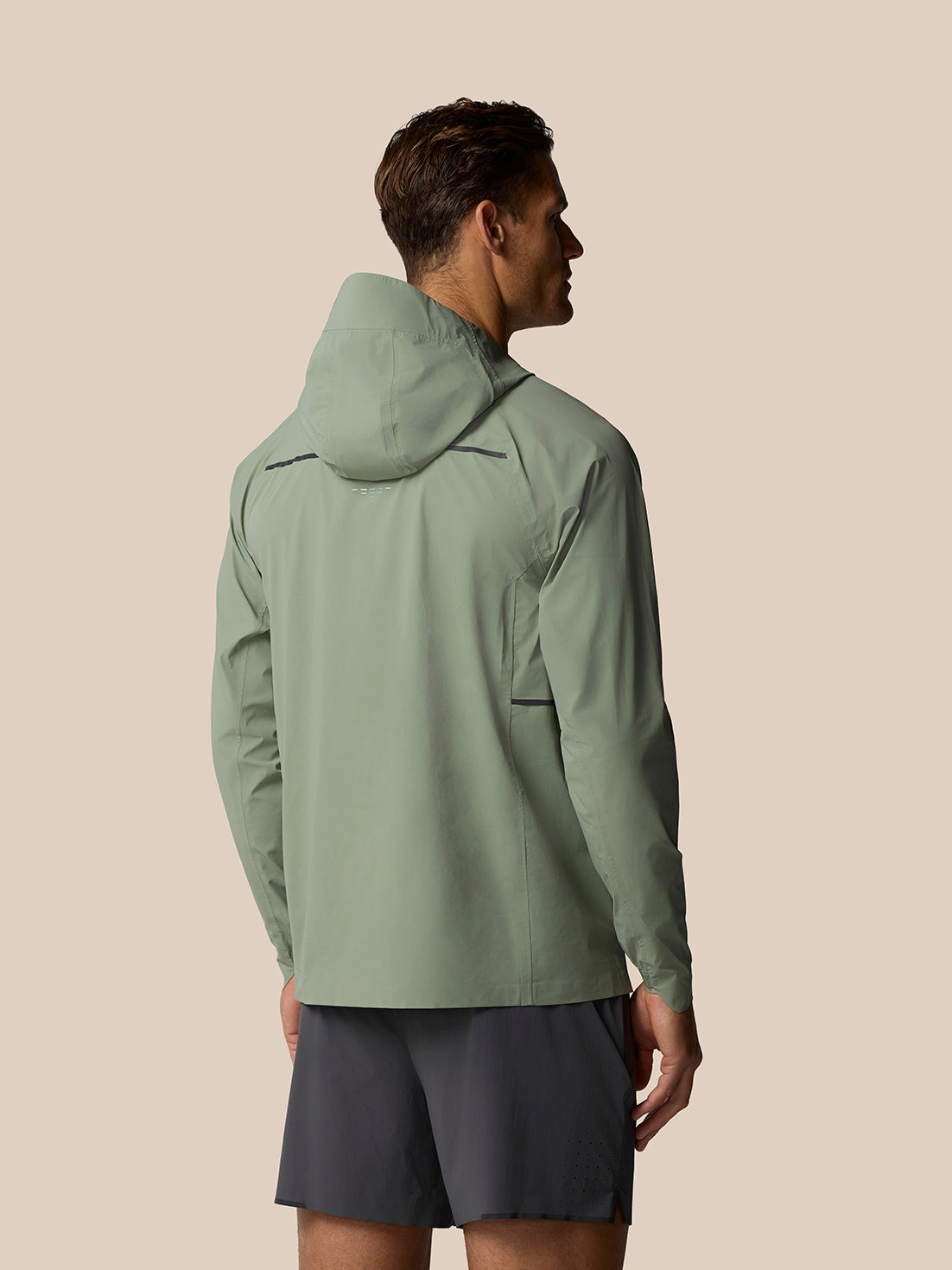 Back view of Zone Training LVS Jacket in Thyme with hood up and layered ventilation back identifier
