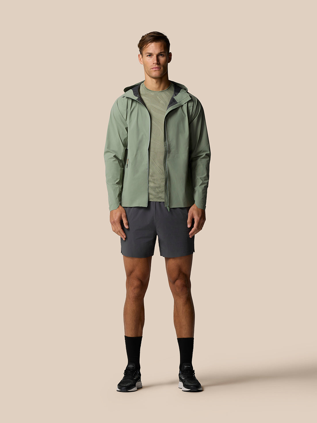 Male model wearing Zone Training LVS Jacket in Thyme with hood down and full zip front view