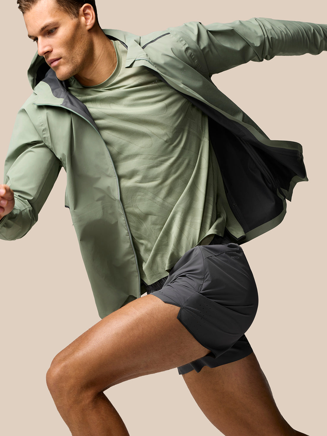 Male model in motion wearing Zone Training LVS Jacket Thyme Black Reflective from side view.