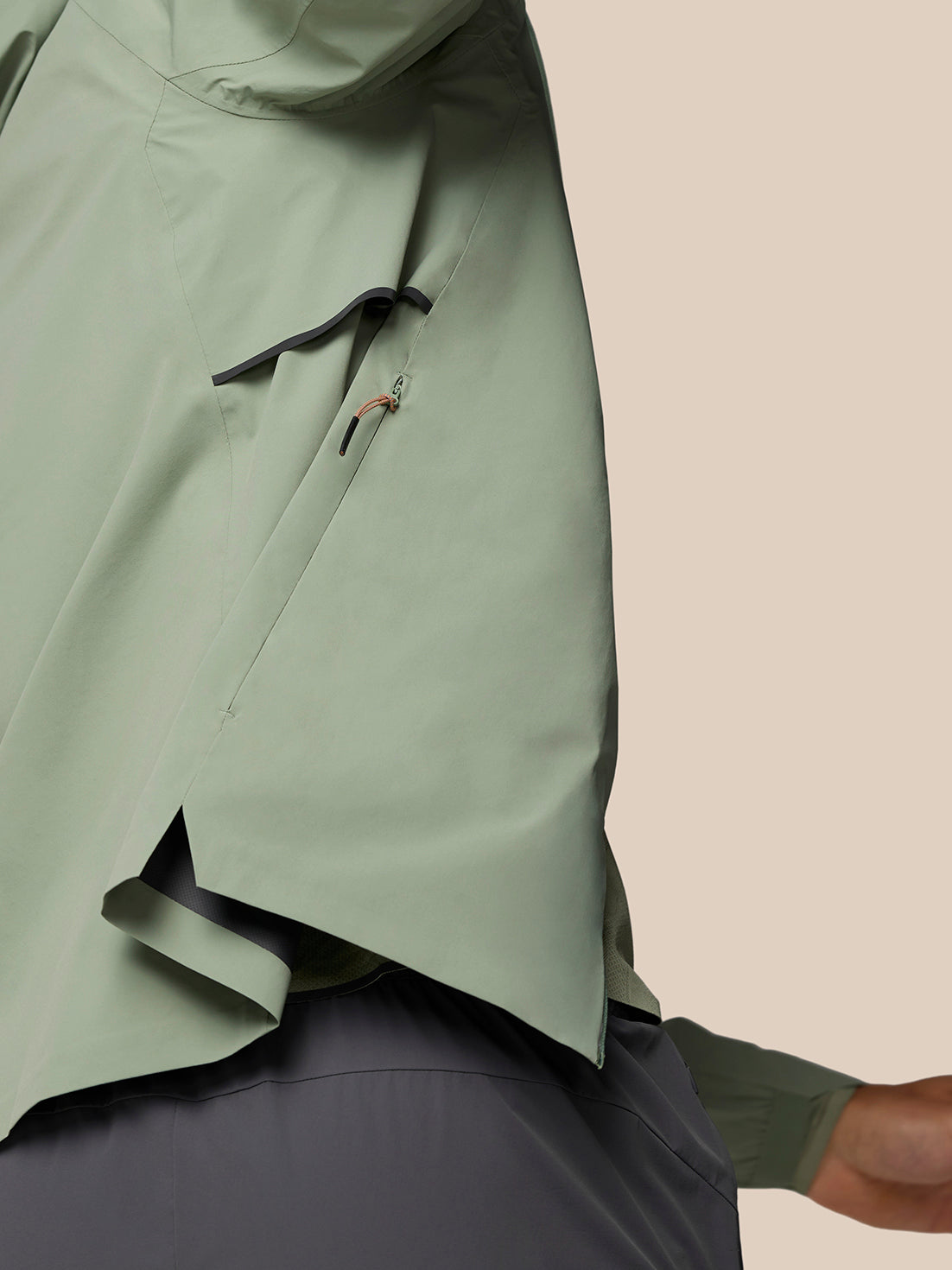 Close up of Zone Training LVS Jacket in Thyme showing hood seam and zip pocket with orange pull