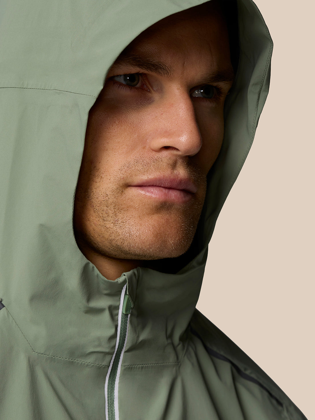 Close up of a man wearing the Zone LVS Jacket with hood up in Thyme, highlighting the hood fit