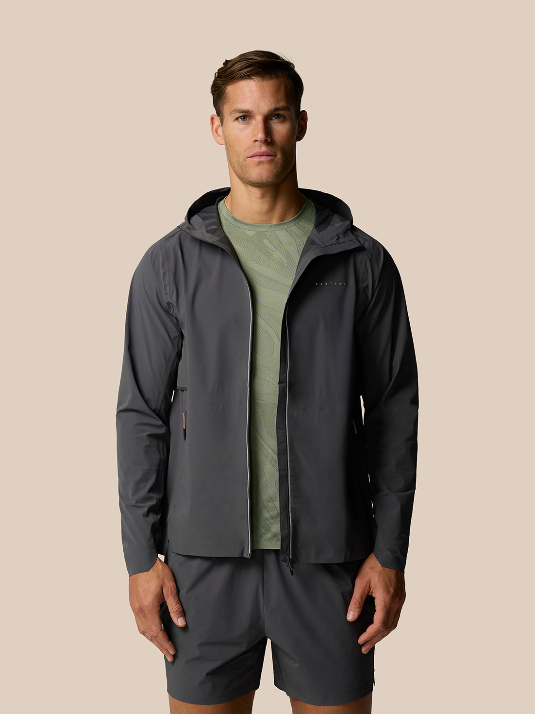Male model in Zone LVS Jacket in gunmetal gray over a green shirt, captured mid motion with the jacket open