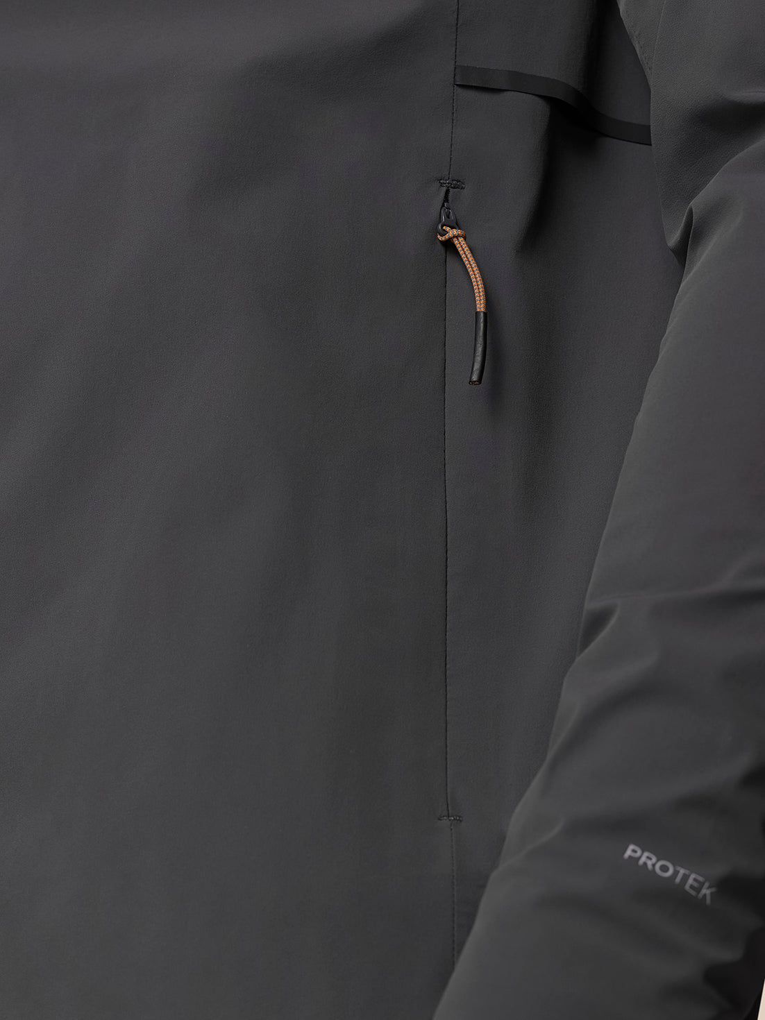Close-up of Gunmetal/Black Reflective Zone LVS Jacket fabric showing front zipper and orange hood drawstring pull.