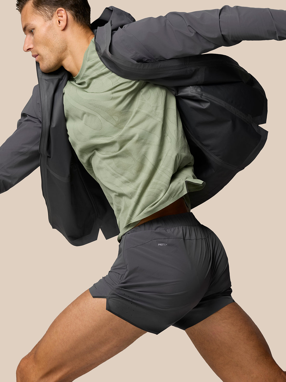 Male model wearing Zone LVS Jacket in gunmetal gray over a green shirt, hood visible and zipper details