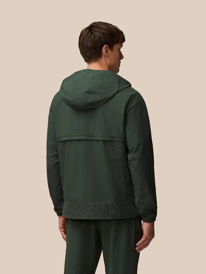 Side-angle front view of a man in the dark green Flex Winterised Woven Jacket with hood