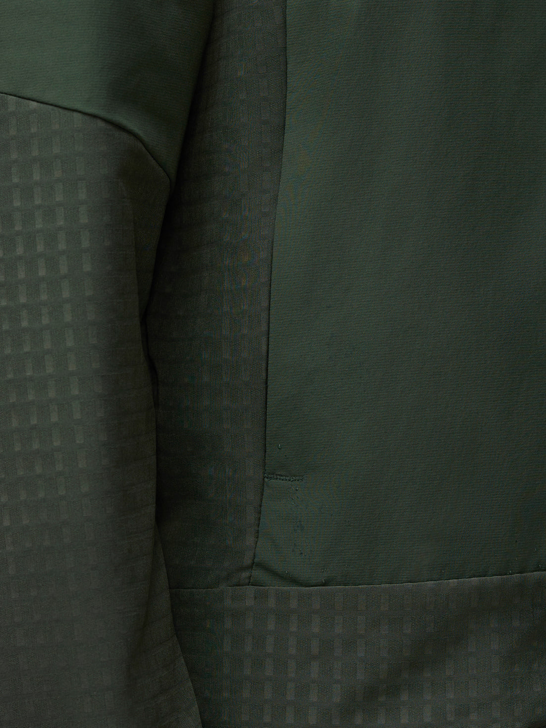 Close up of dark green Flex Winterised Woven Jacket fabric showing a subtle grid pattern and seam.