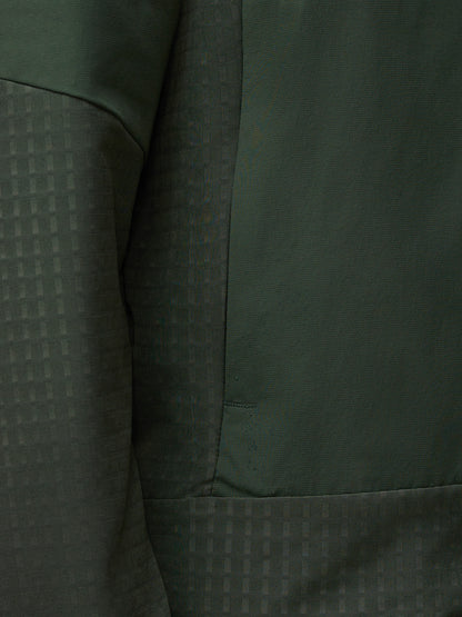 Close up of dark green Flex Winterised Woven Jacket fabric showing a subtle grid pattern and seam.