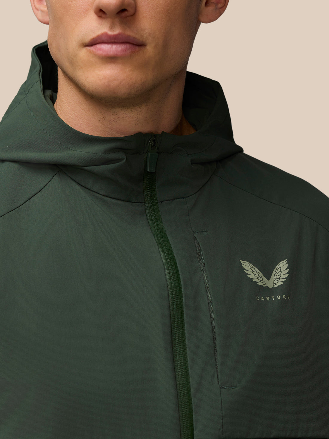 Close-up of the dark green Flex Winterised Woven Jacket highlighting the front zipper and Castore logo on the left chest.