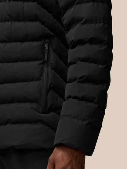 Close-up of black lightweight puffer jacket with horizontal quilting and a zippered pocket