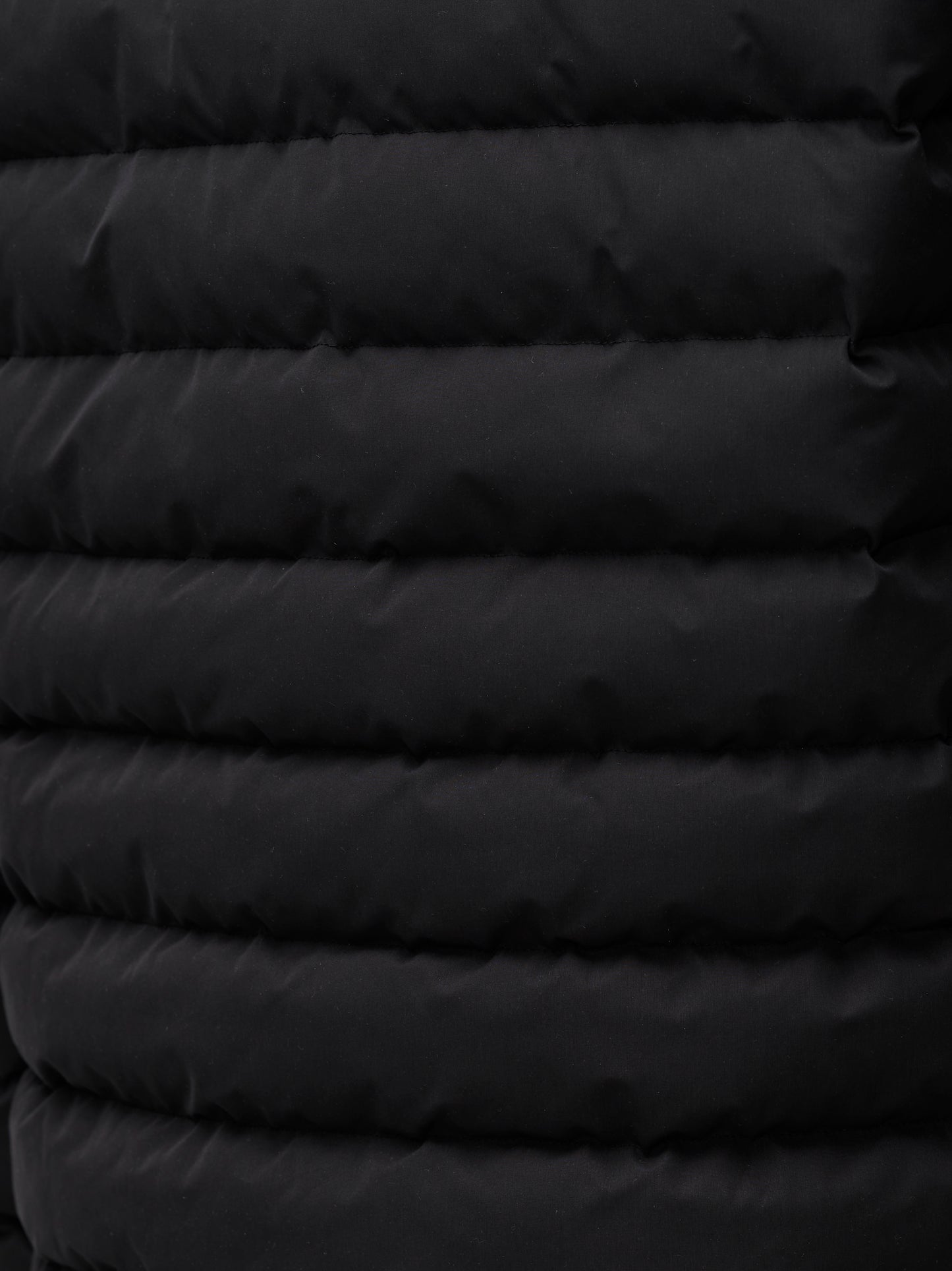 Close up of black quilted exterior from a men's lightweight puffer jacket.