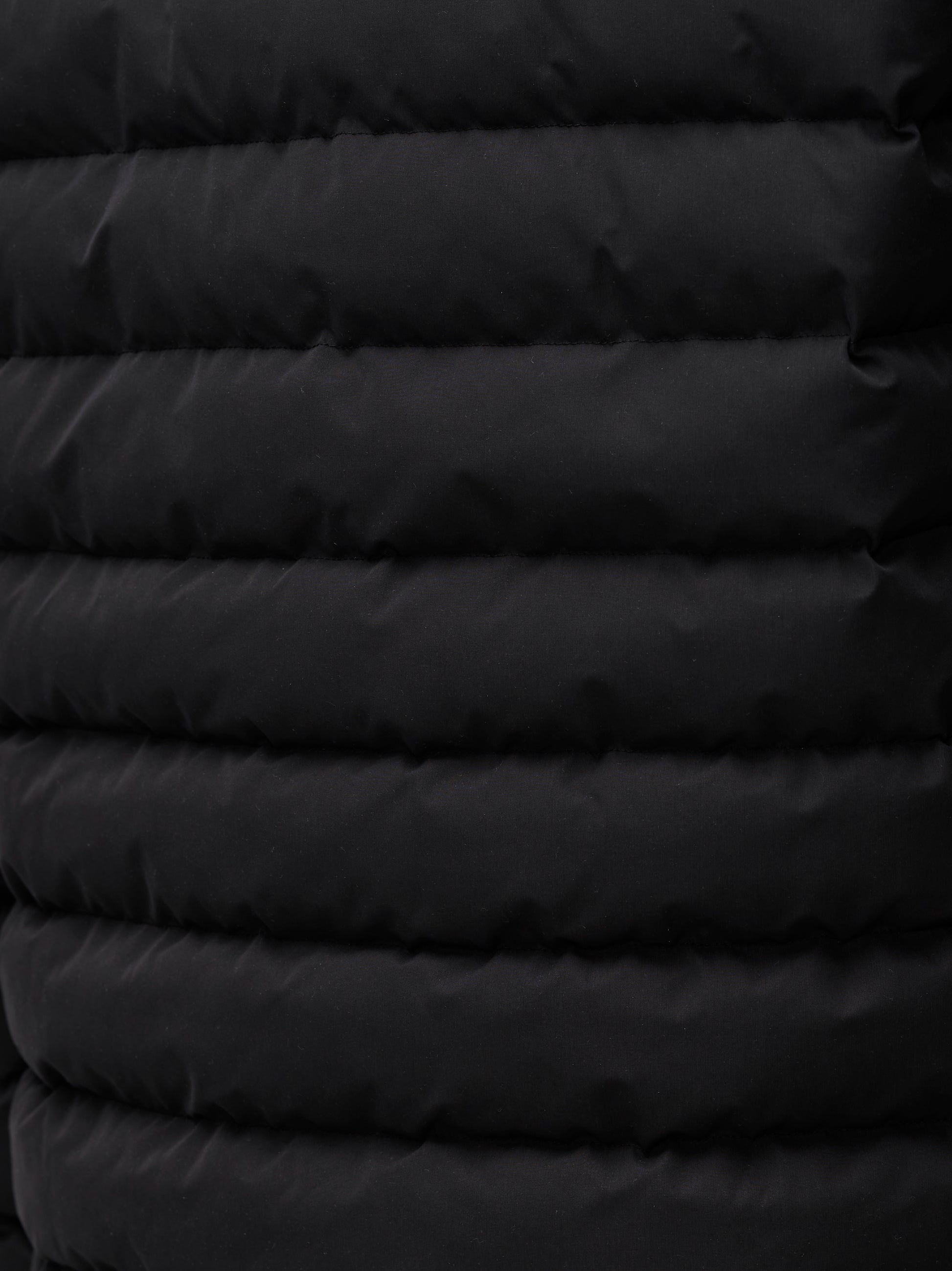 Close up of black quilted exterior from a men's lightweight puffer jacket.